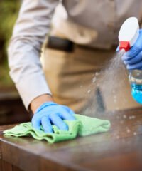 Close-up of waitress cleaning tables with disinfectant due to coronavirus epidemic.